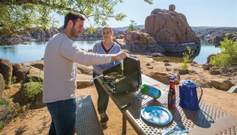 Image of people camping and using a refillable propane cylinder